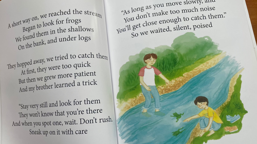 Open book with a colorful illustration of two people by a river on a wooden surface.